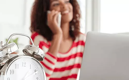 Primer plano de un reloj y empleada trabajando, ilustración de la nueva ley de control horario 2025